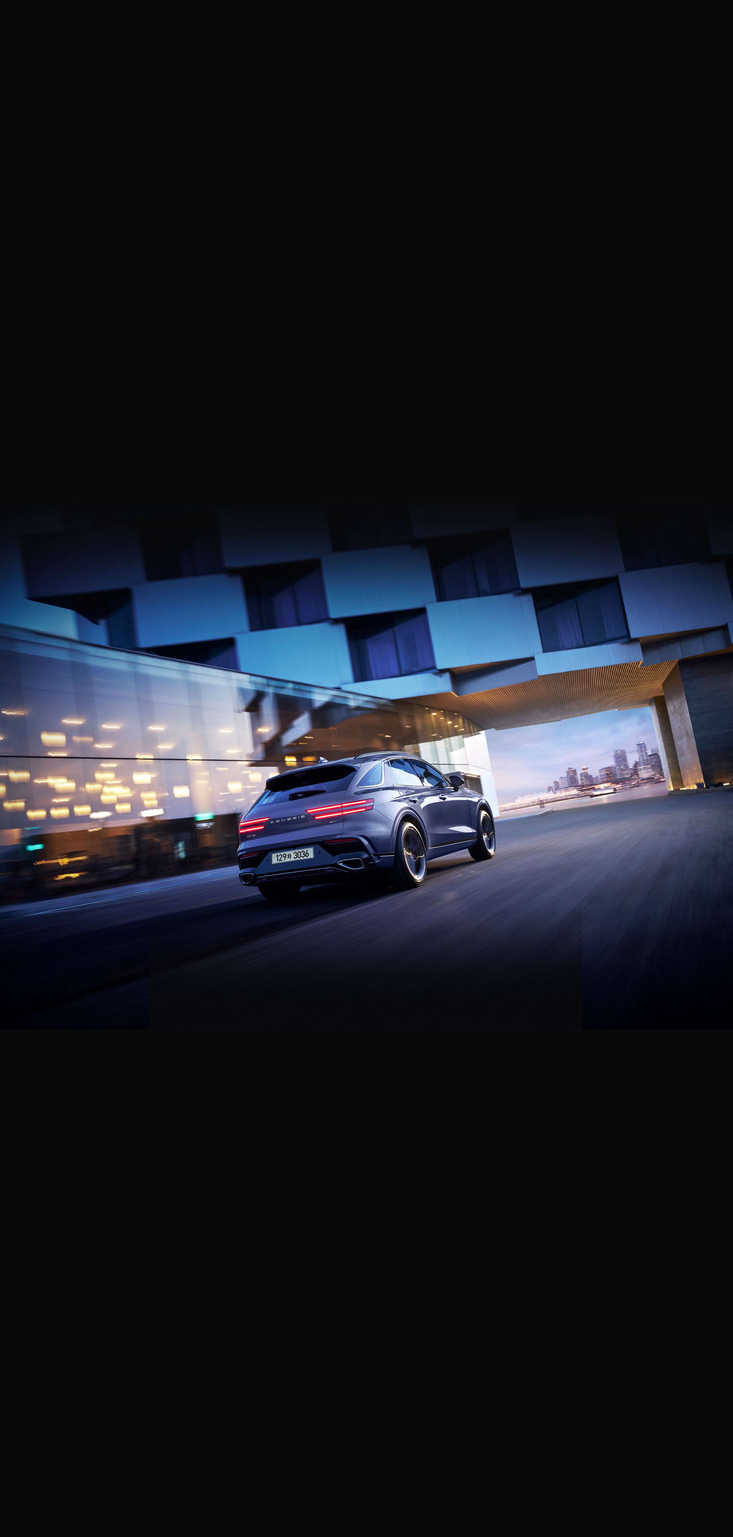 This is a view from the rear of the GV70 driving through a city illuminated by city lights at night.